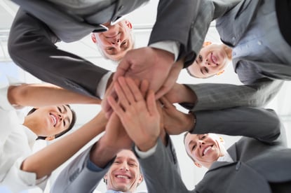 In-house business team standing with hands stacked together in an office