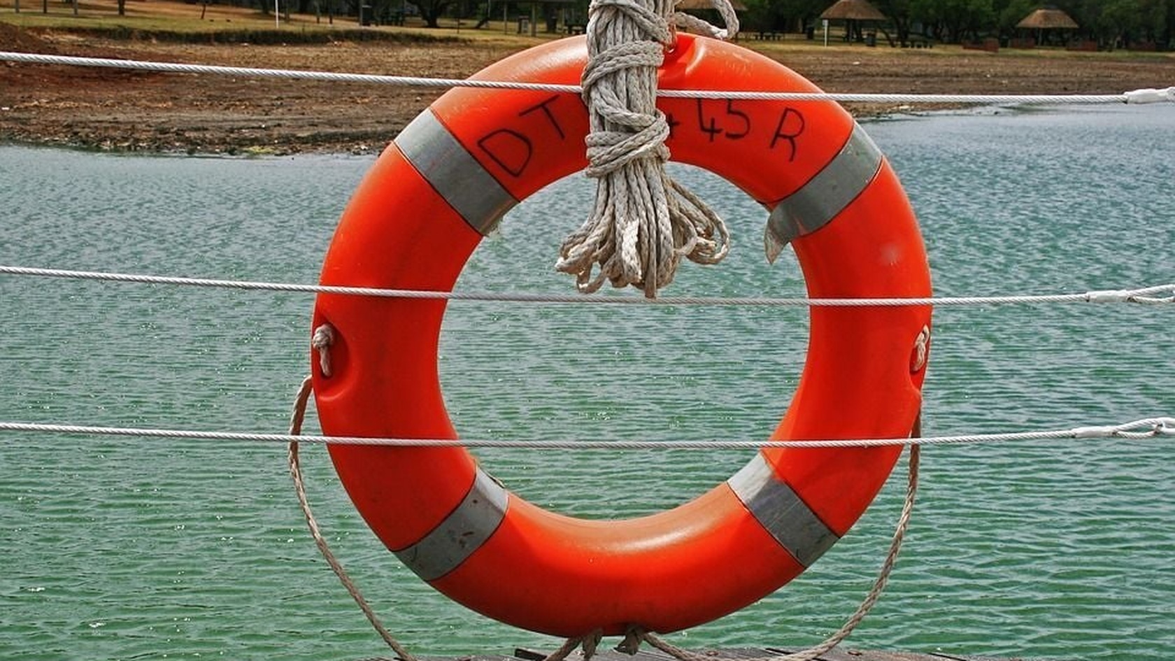 Orange life ring secured with ropes beside the water, illustrating preparedness and business recovery.