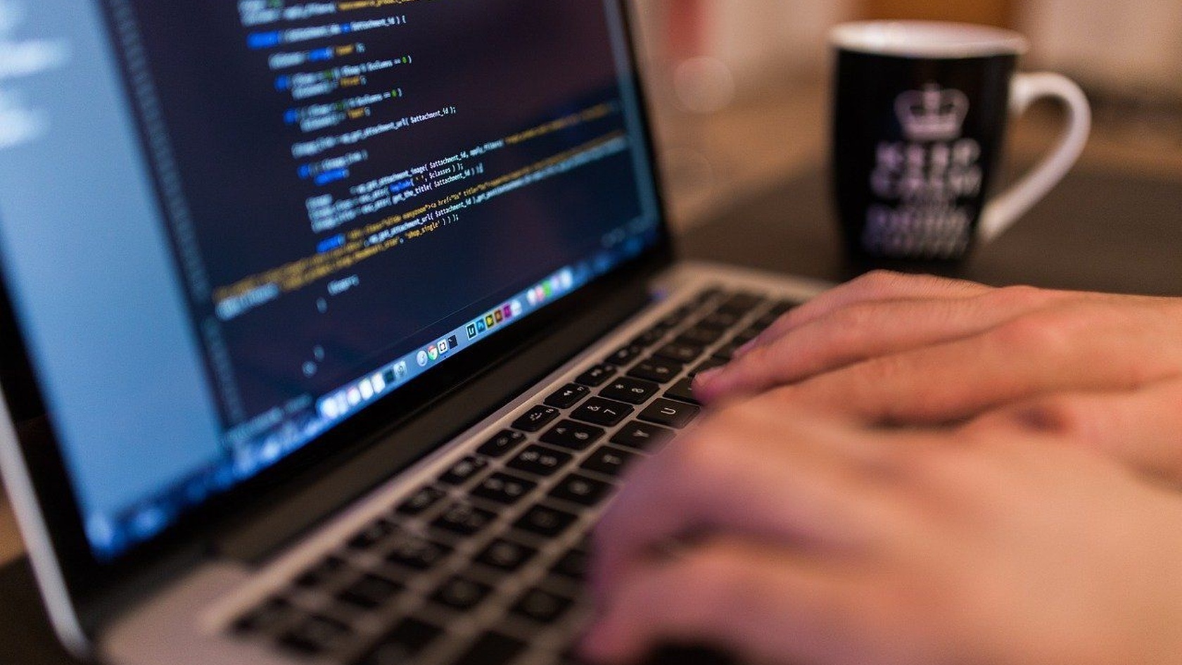 Hands typing code on a laptop, illustrating secure software development and system protection covered by the ISM guidelines.