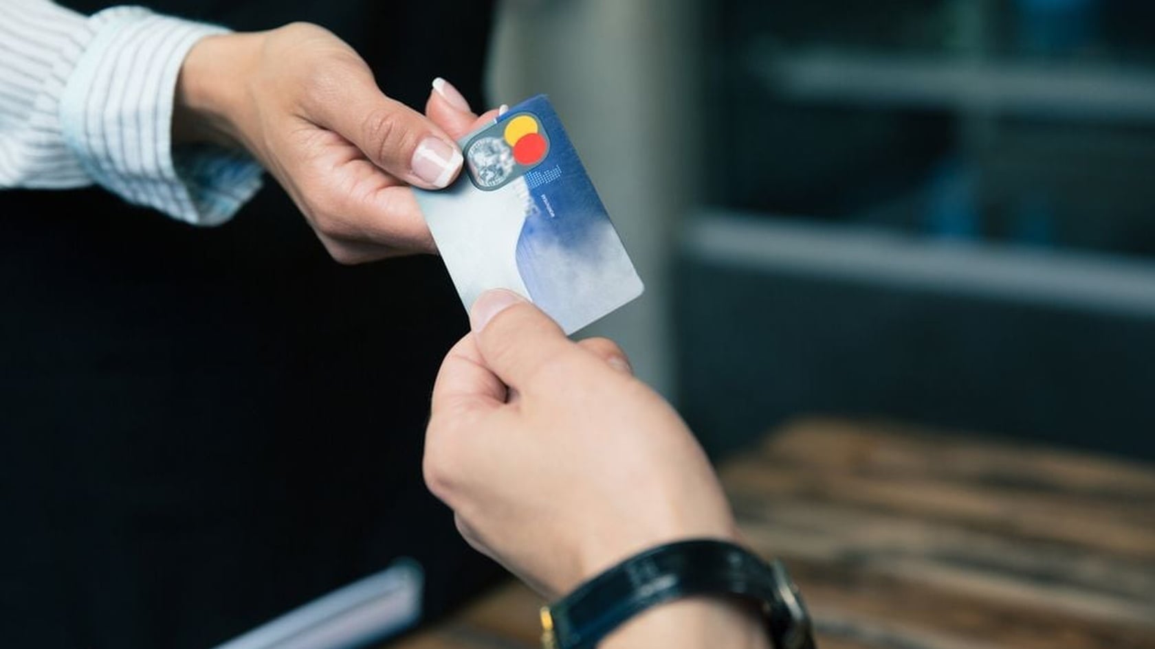 Hands exchanging a credit card during a restaurant payment, illustrating PCI DSS cardholder data security.