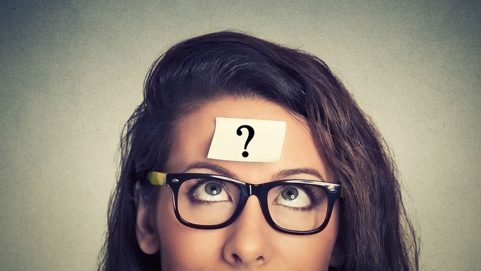 Woman wearing glasses with a question-mark note on her forehead, illustrating common PCI DSS questions.