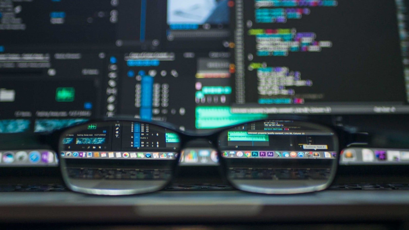 Glasses resting in front of monitors displaying source code, illustrating penetration testing during software development.