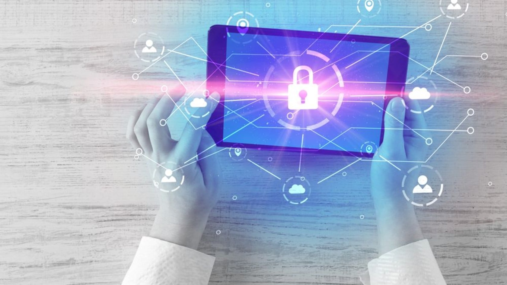 Hands holding a tablet showing a padlock surrounded by network connection icons, representing a CISO safeguarding an organisation’s information security.